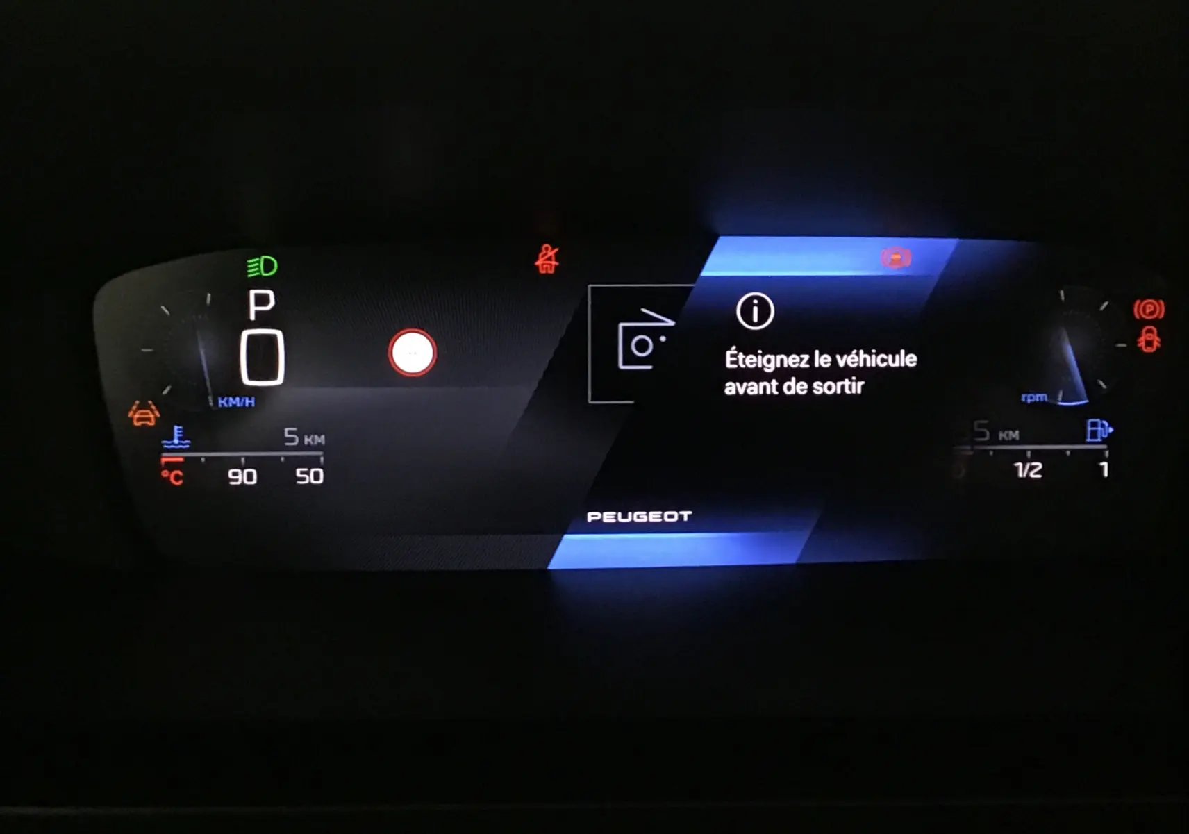 Tableau de bord numérique Peugeot 308 blanc Okenite affichant un message d'arrêt et les indicateurs de vitesse et carburant.