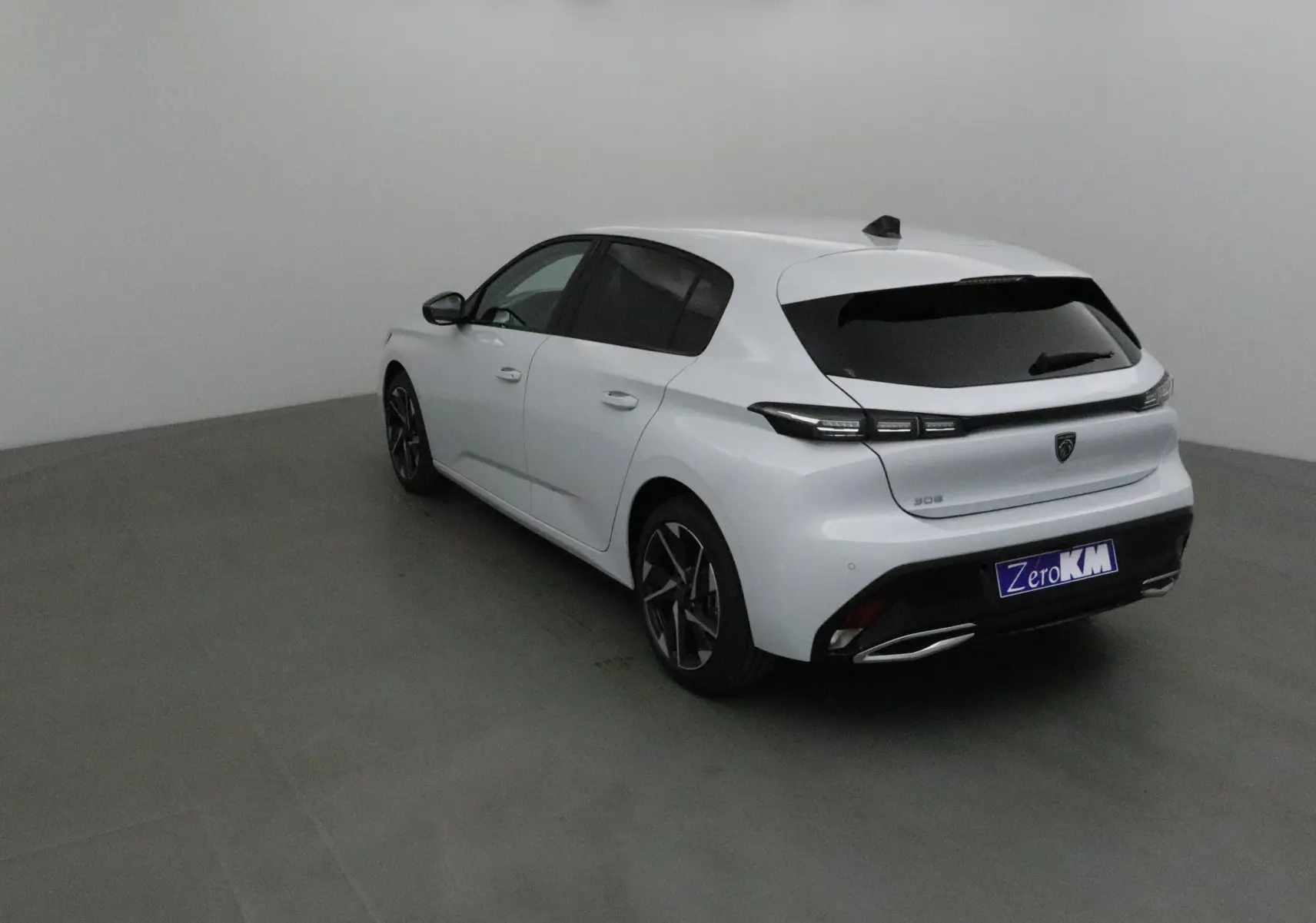 Peugeot 308 blanc Okenite vue 3/4 arrière droit avec vitres teintées et jantes alliage noires.