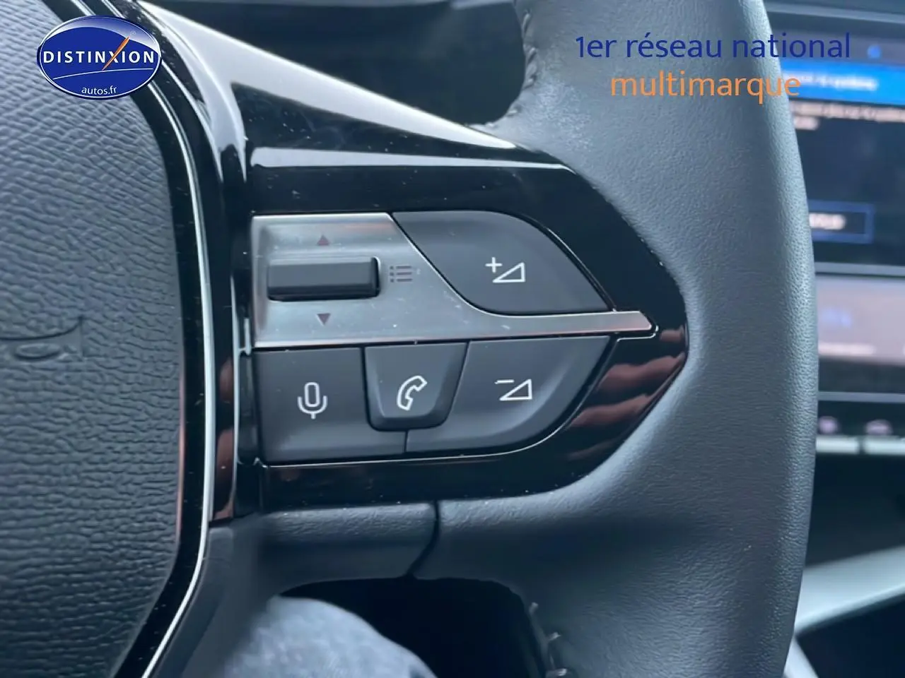Gros plan sur les commandes au volant à droite d’un Peugeot 308 gris sélénite, avec écran tactile en arrière-plan flou.