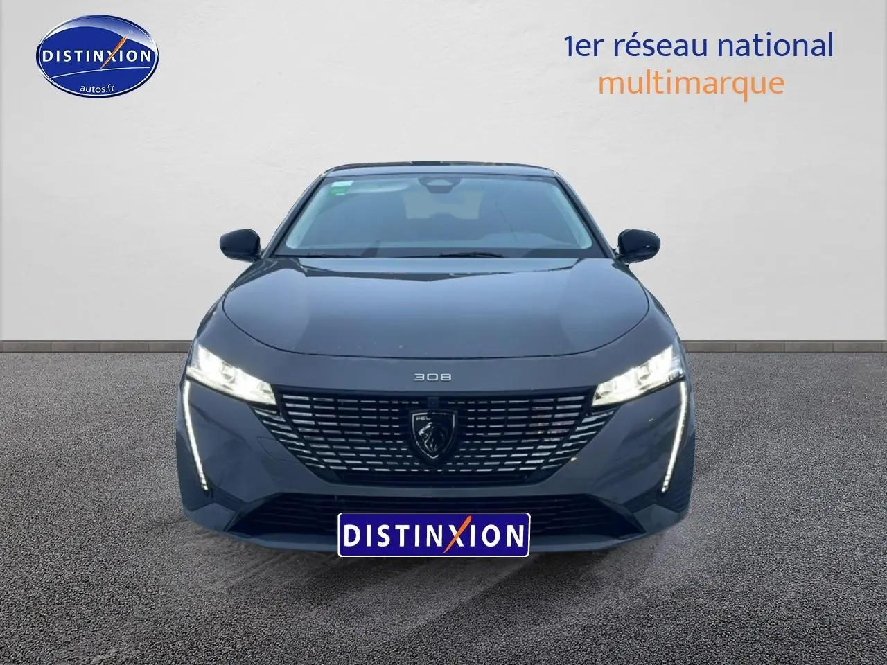 Vue frontale d'une Peugeot 308 gris sélénite 2025 avec phares LED allumés et calandre distinctive.