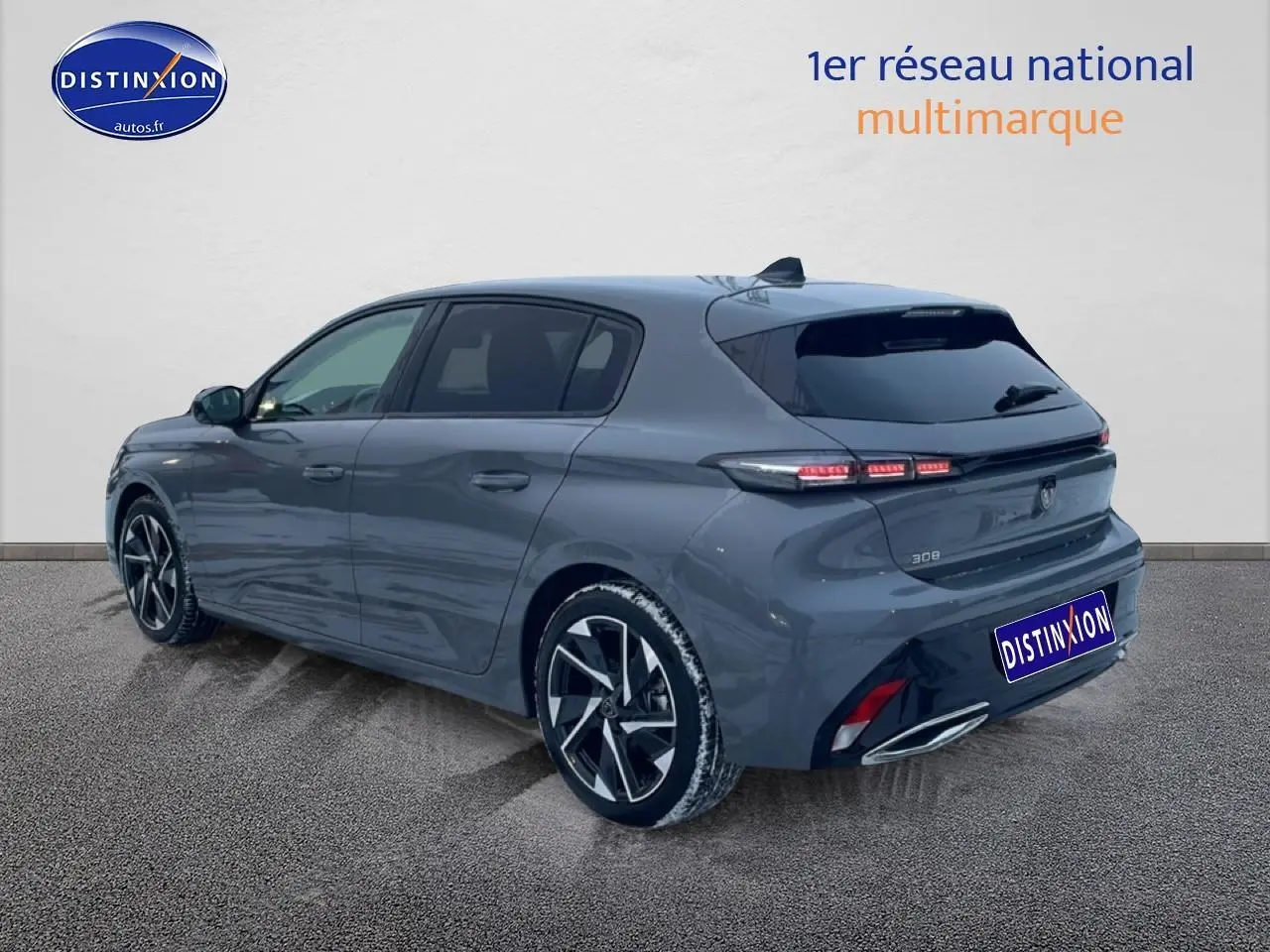 Vue 3/4 arrière droite d'une Peugeot 308 gris sélénite avec jantes alu et feux arrière LED allumés.