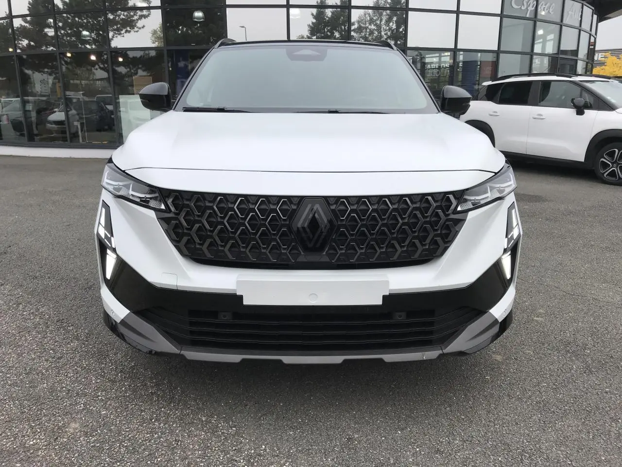 Vue de face du Renault Austral blanc avec calandre noire à motif hexagonal et feux LED en forme de T.