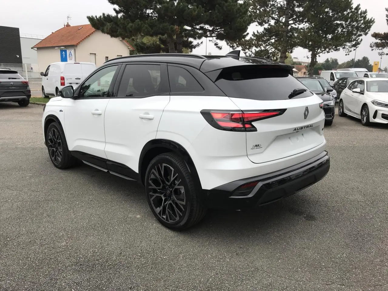 Vue 3/4 arrière droite du Renault Austral blanc bi-ton avec jantes noires et toit noir satin.