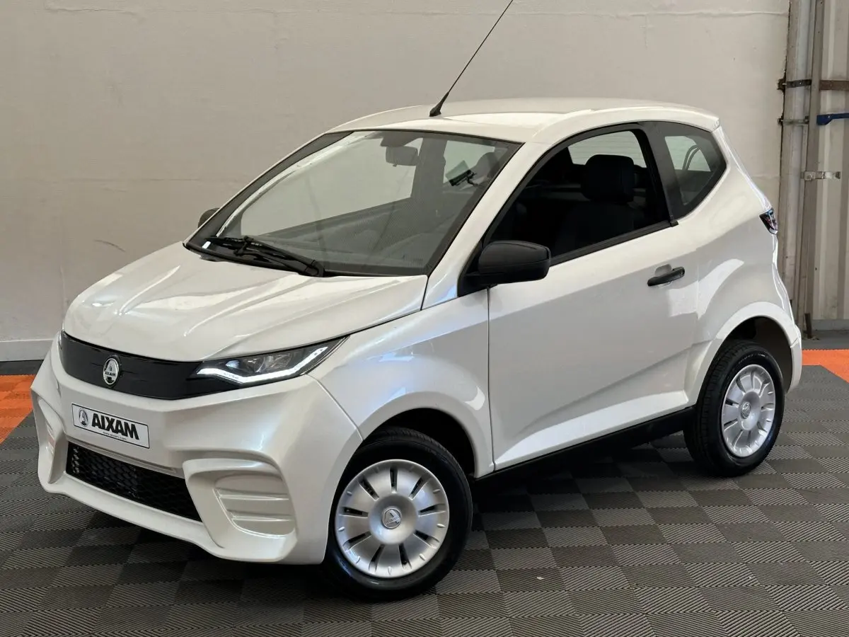 Vue 3/4 avant droit d'une Aixam Ambition E City Pack blanche 2026 avec rétroviseur caméra côté conducteur.