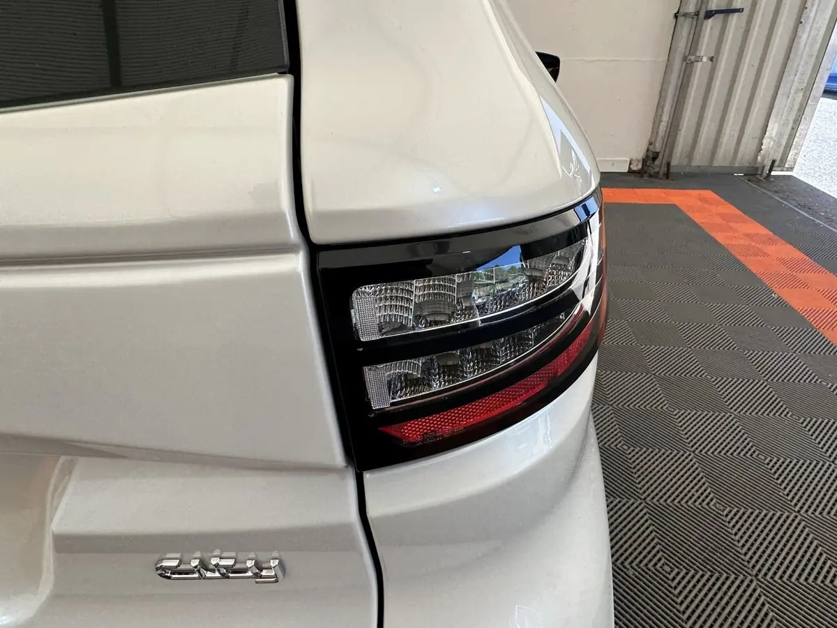 Gros plan sur le feu arrière droit blanc brillant de l'AIXAM AMBITION E CITY PACK 2026 avec détails noirs et rouge.