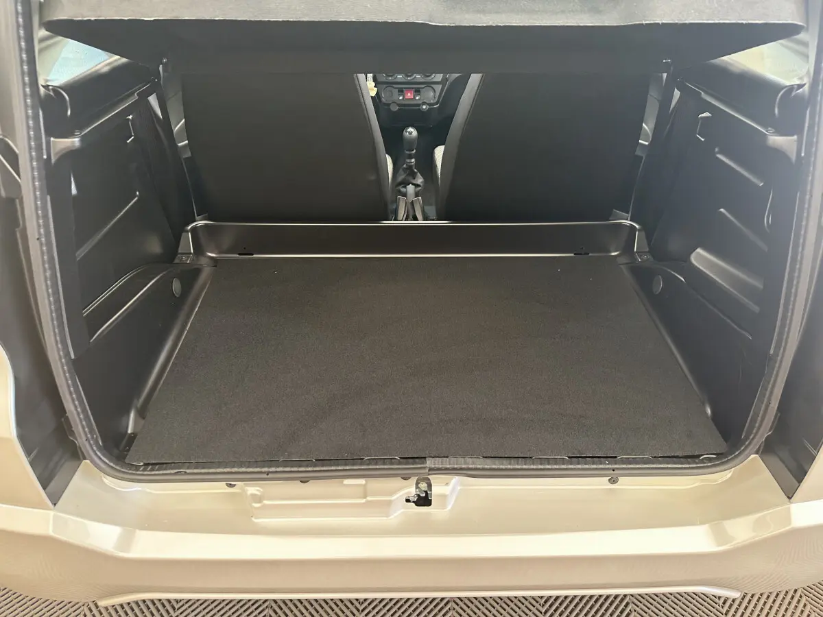 Coffre ouvert vu de l'arrière d'une AIXAM AMBITION E CITY PACK blanche, montrant l'espace de chargement et l'intérieur noir.