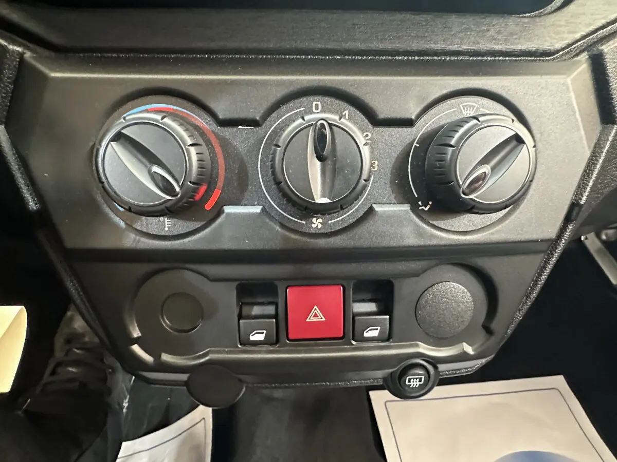 Vue rapprochée des commandes de climatisation et des boutons de sécurité du tableau de bord de l'AIXAM AMBITION E CITY PACK 2026.