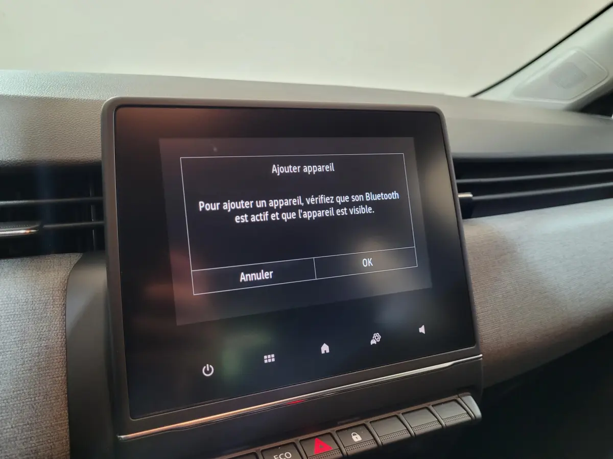 Écran tactile central affichant un message Bluetooth dans l'habitacle gris clair d'une Renault Clio Evolution 2025.