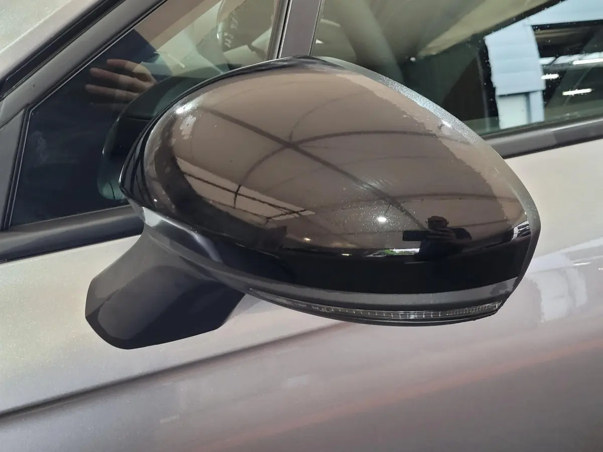 Rétroviseur côté gauche noir brillant sur Renault Clio gris foncé, vue rapprochée sur la portière avant.