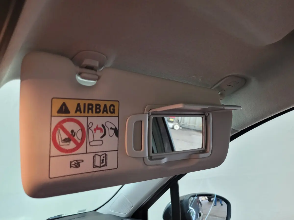 Détail du pare-soleil côté conducteur avec miroir intégré et avertissement airbag dans une Renault Clio gris foncé, vue intérieure.