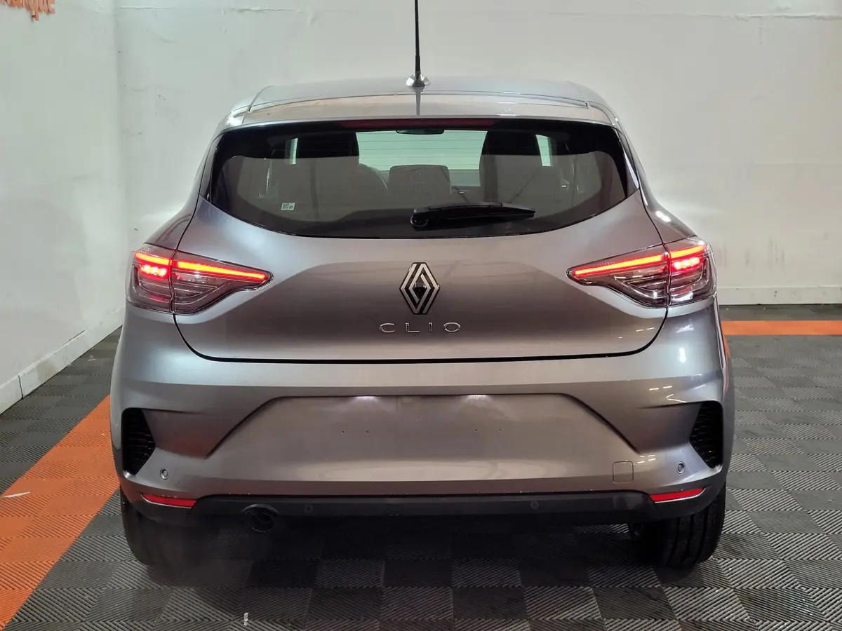 Vue arrière d'une Renault Clio gris foncé avec feux arrière LED allumés dans un garage.