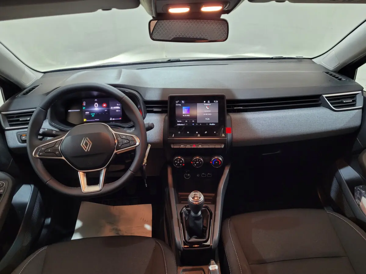 Vue intérieure avant du tableau de bord gris foncé de la Renault Clio Evolution Blue dCi 100 avec volant cuir et écran tactile central.
