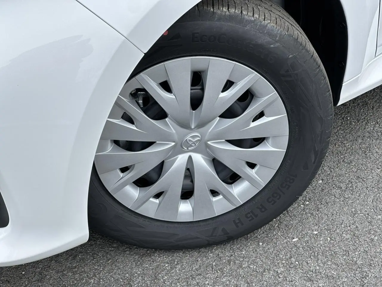 Gros plan sur la roue avant gauche de la Toyota Yaris Hybride blanche avec enjoliveur gris et pneu EcoContact 6.