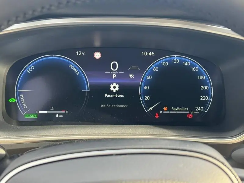 Tableau de bord numérique de Toyota Corolla 2025, affichage vitesse et jauge hybride, vue frontale rapprochée.