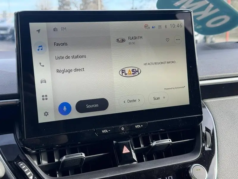 Écran tactile central de la Toyota Corolla 2025 affichant la radio FM avec commandes de volume intégrées, vue intérieure frontale.