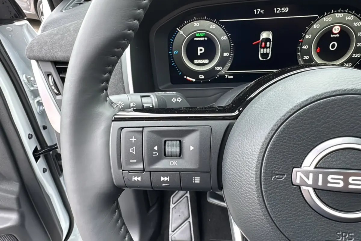 Gros plan sur le volant cuir noir et le tableau de bord numérique du Nissan Qashqai E-POWER 205 Tekna Plus blanc lunaire.