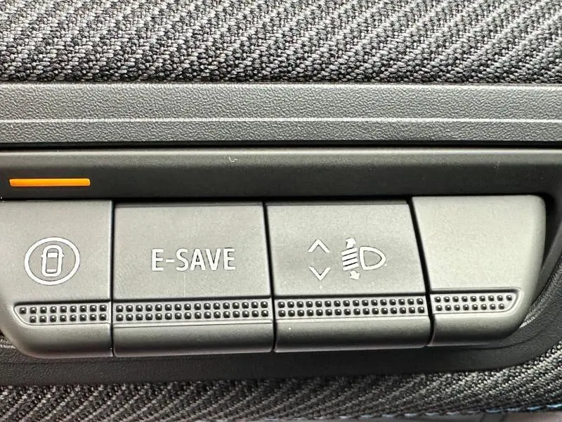 Gros plan sur les boutons de commande du tableau de bord du Renault Captur 2025, avec fonction E-SAVE et réglage des phares.