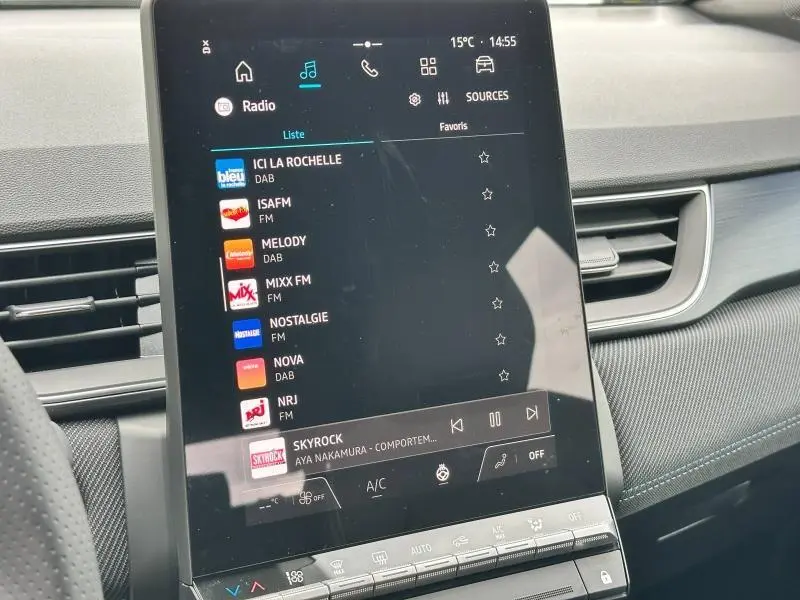 Écran tactile central du tableau de bord du Renault Captur 2025, affichant les stations radio, avec détails intérieurs en noir et gris.