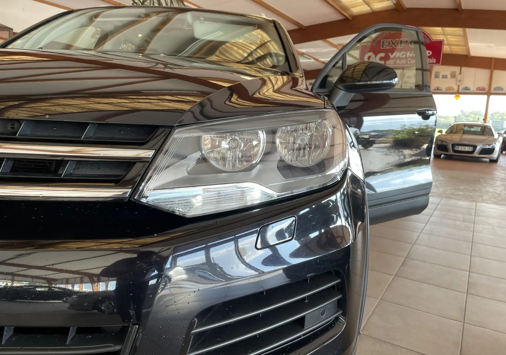 Gros plan sur l'avant droit noir brillant d'un Volkswagen Touareg 2012 avec porte ouverte dans un showroom.