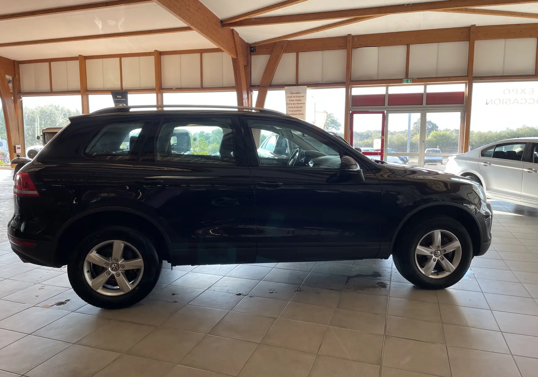 Profil côté gauche d'un Volkswagen Touareg noir 2012 en showroom, soulignant ses lignes robustes et jantes alliage.