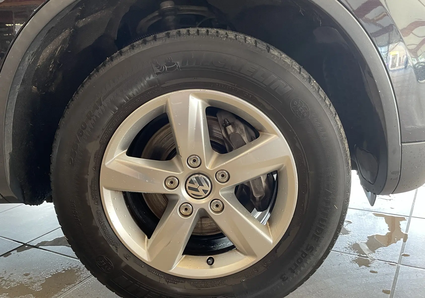 Vue rapprochée de la roue arrière droite noire d'un Volkswagen Touareg 2012, soulignant l'arche de roue et le passage de roue.