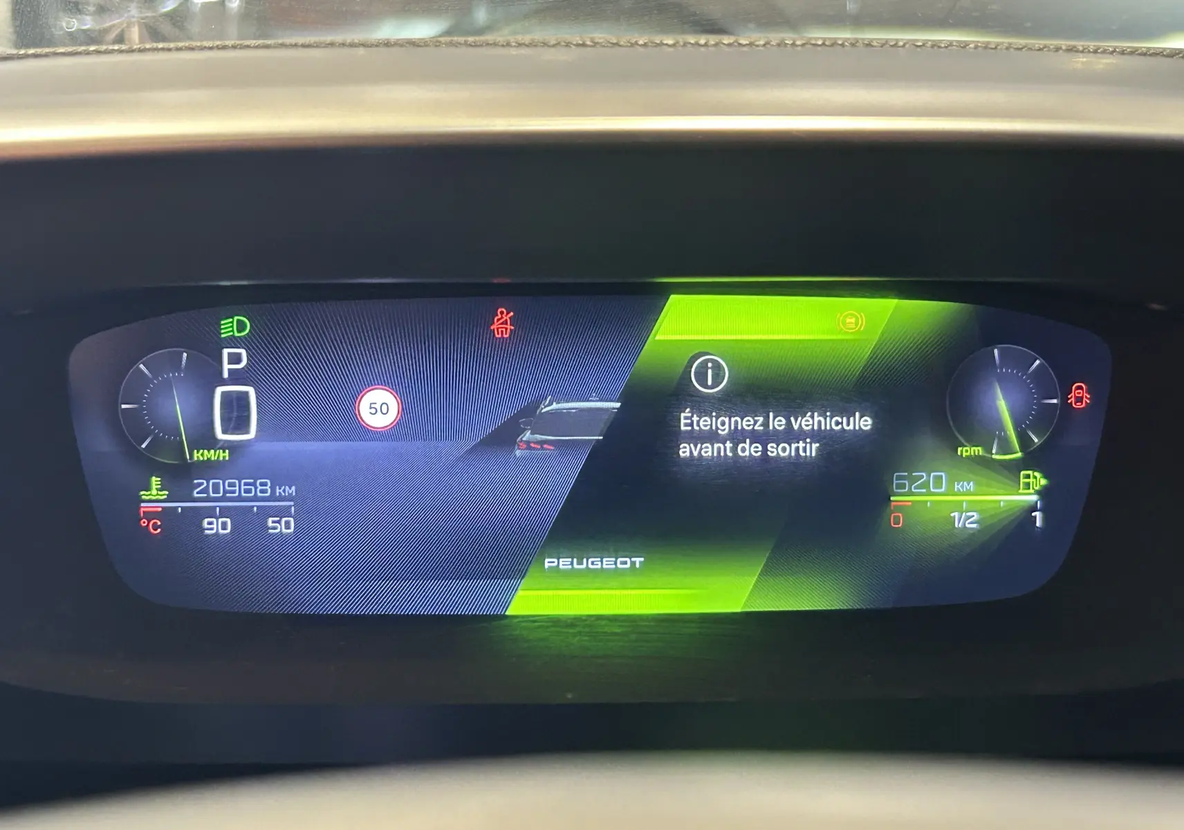 Affichage numérique du tableau de bord du Peugeot 308 SW 2024, avec message d'arrêt et jauges en vert et bleu.