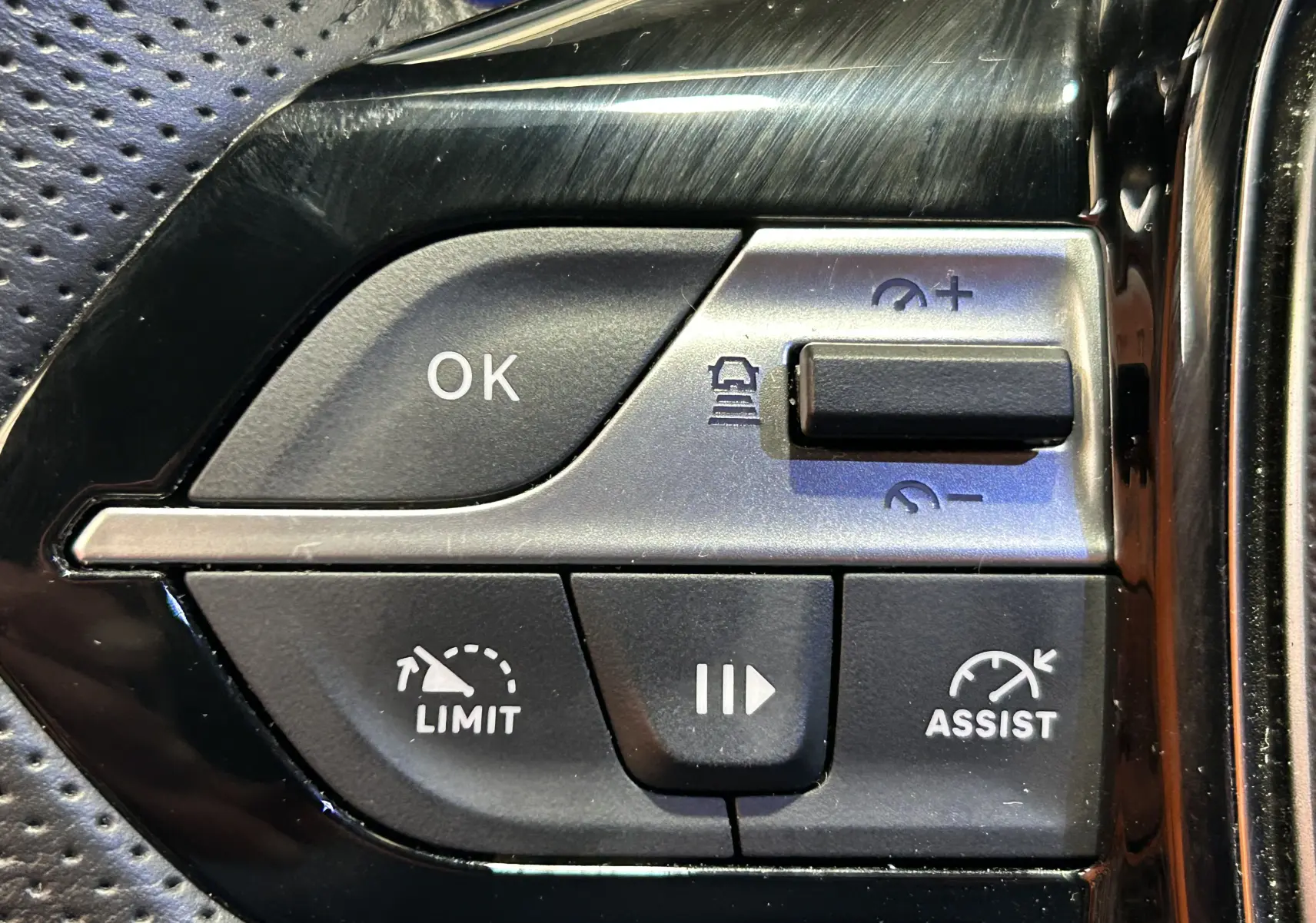 Gros plan sur les commandes au volant du Peugeot 308 SW 2024, boutons de limitation et assistance de vitesse visibles.