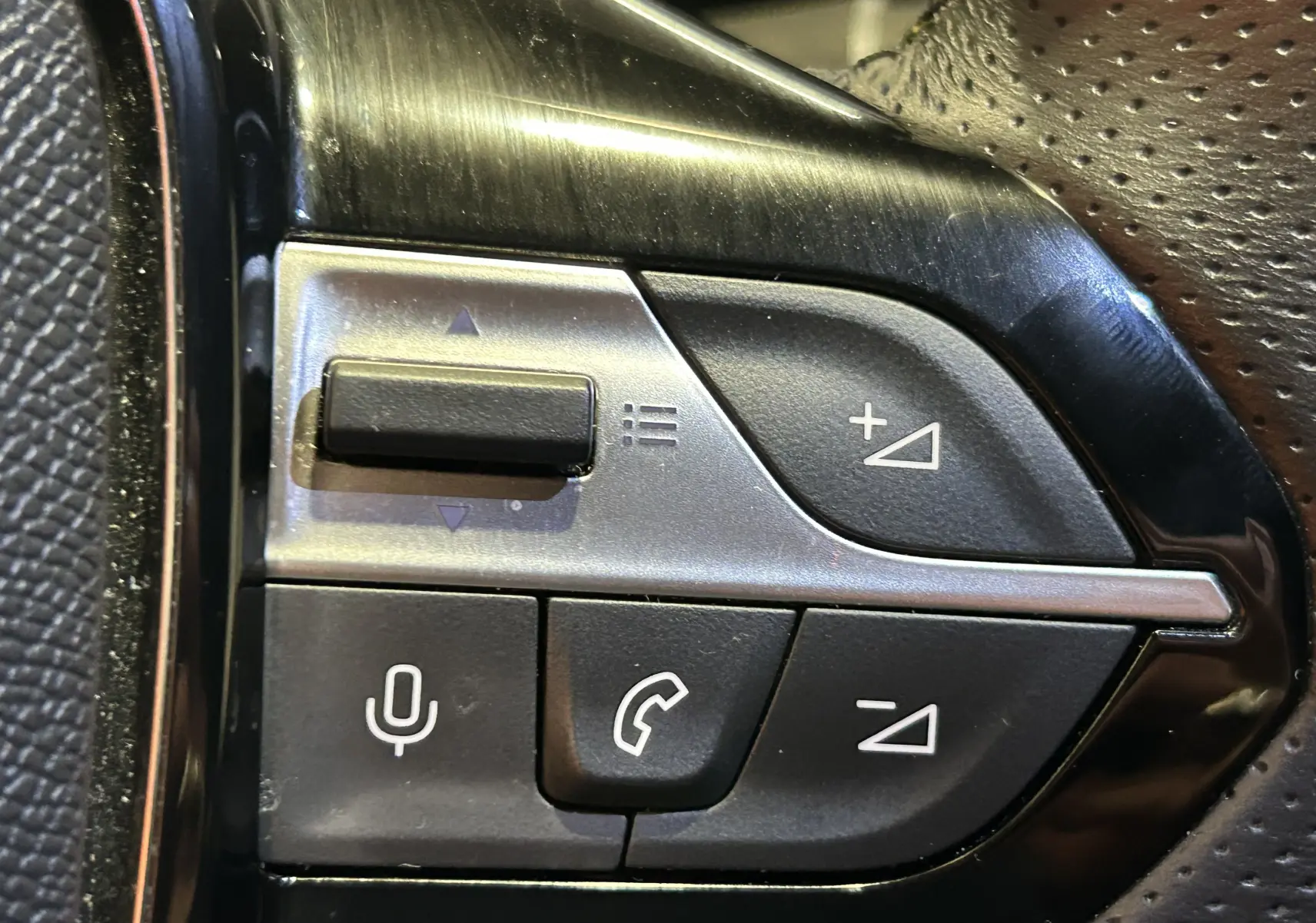 Gros plan sur les commandes vocales et téléphone du volant en cuir perforé de la Peugeot 308 SW gris Sellenium.