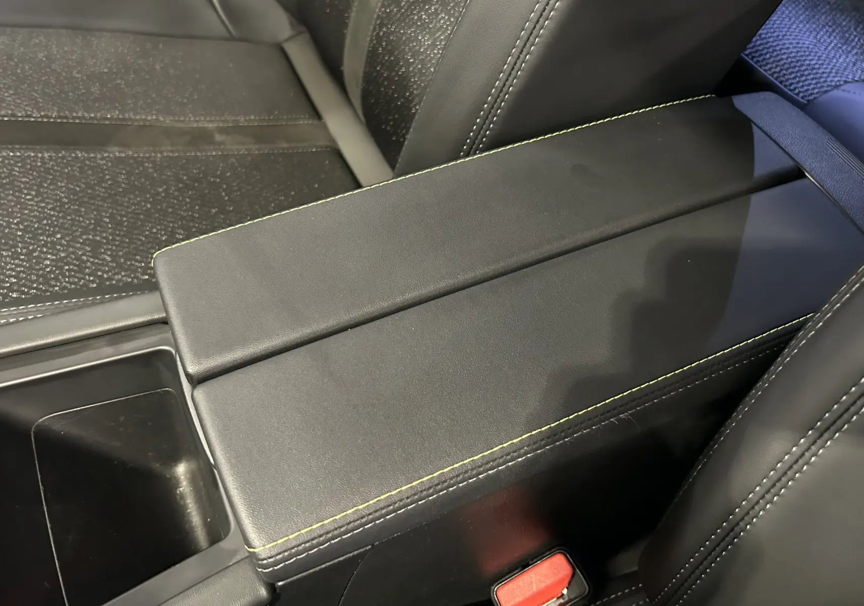 Accoudoir central noir avec surpiqûres vertes et sièges en cuir noir de la Peugeot 308 SW 2024 finition GT.