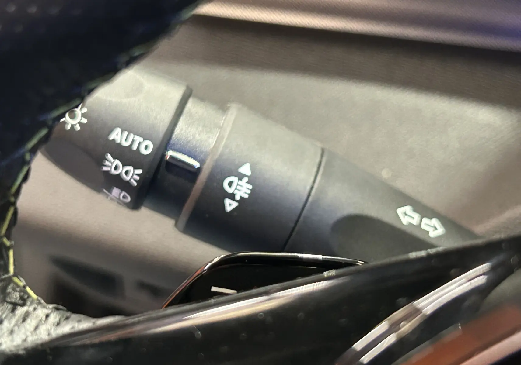 Gros plan sur la manette des feux et clignotants côté gauche du volant d'une Peugeot 308 SW gris Sellenium 2024.