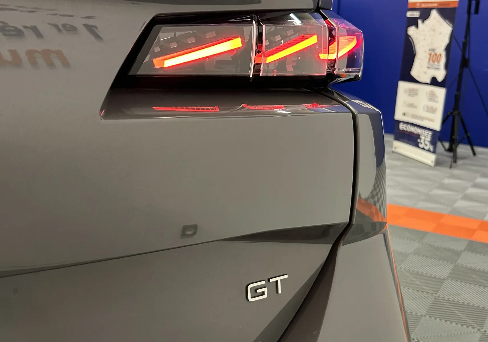 Gros plan sur le feu arrière droit allumé d'une Peugeot 308 SW III GT gris Sellenium avec logo GT visible.