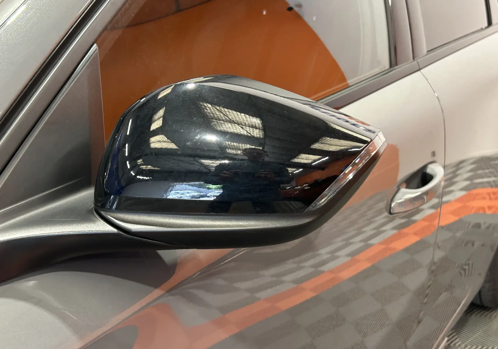 Rétroviseur noir brillant côté gauche d'une Peugeot 308 SW III GT BlueHDi 130 gris Sellenium, vue rapprochée.