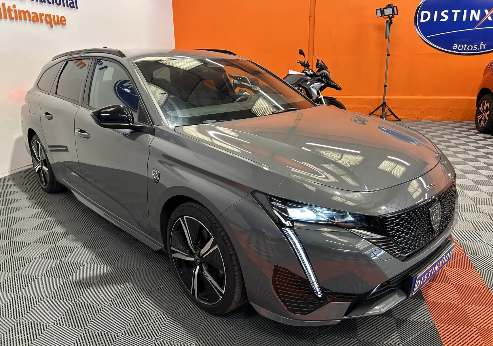 Peugeot 308 SW gris Sellenium vue 3/4 avant droit avec feux LED allumés et jantes alliage noires.