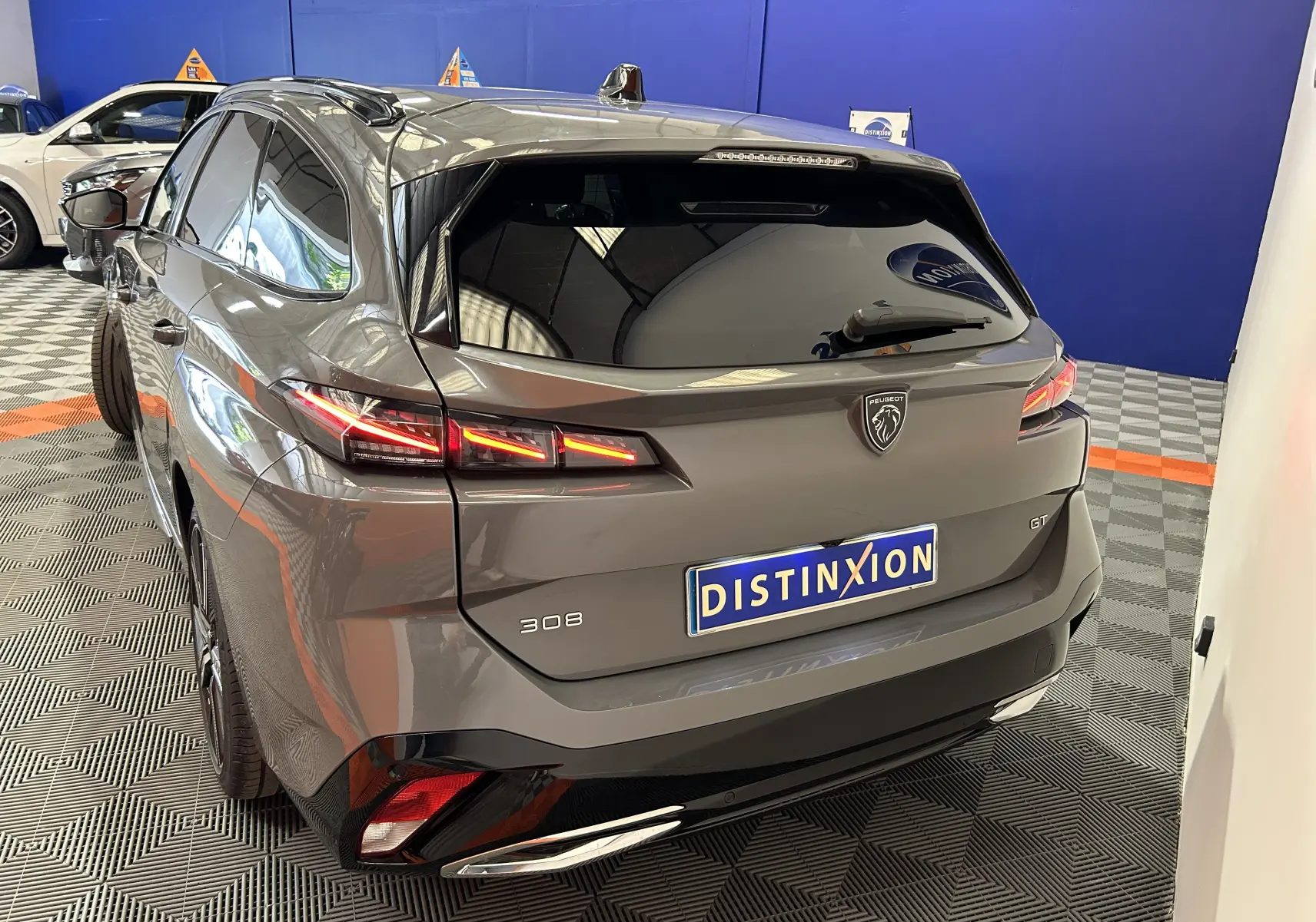 Vue 3/4 arrière droite d'une Peugeot 308 SW III GT gris Sellenium avec feux LED et logo distinctif sur hayon.