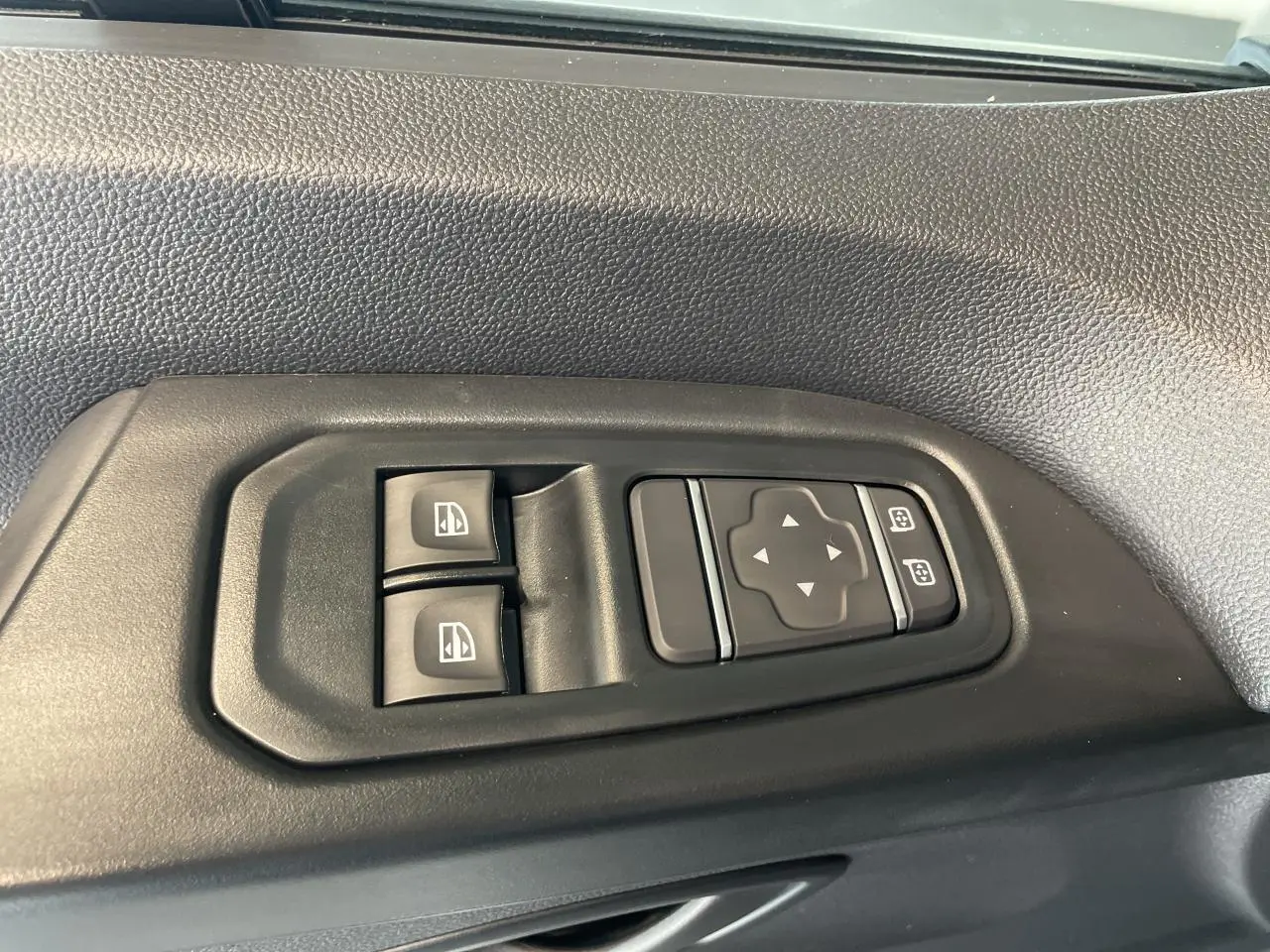 Commandes électriques des vitres et rétroviseurs sur la portière côté gauche d'un Renault Trafic Fourgon gris Comète.