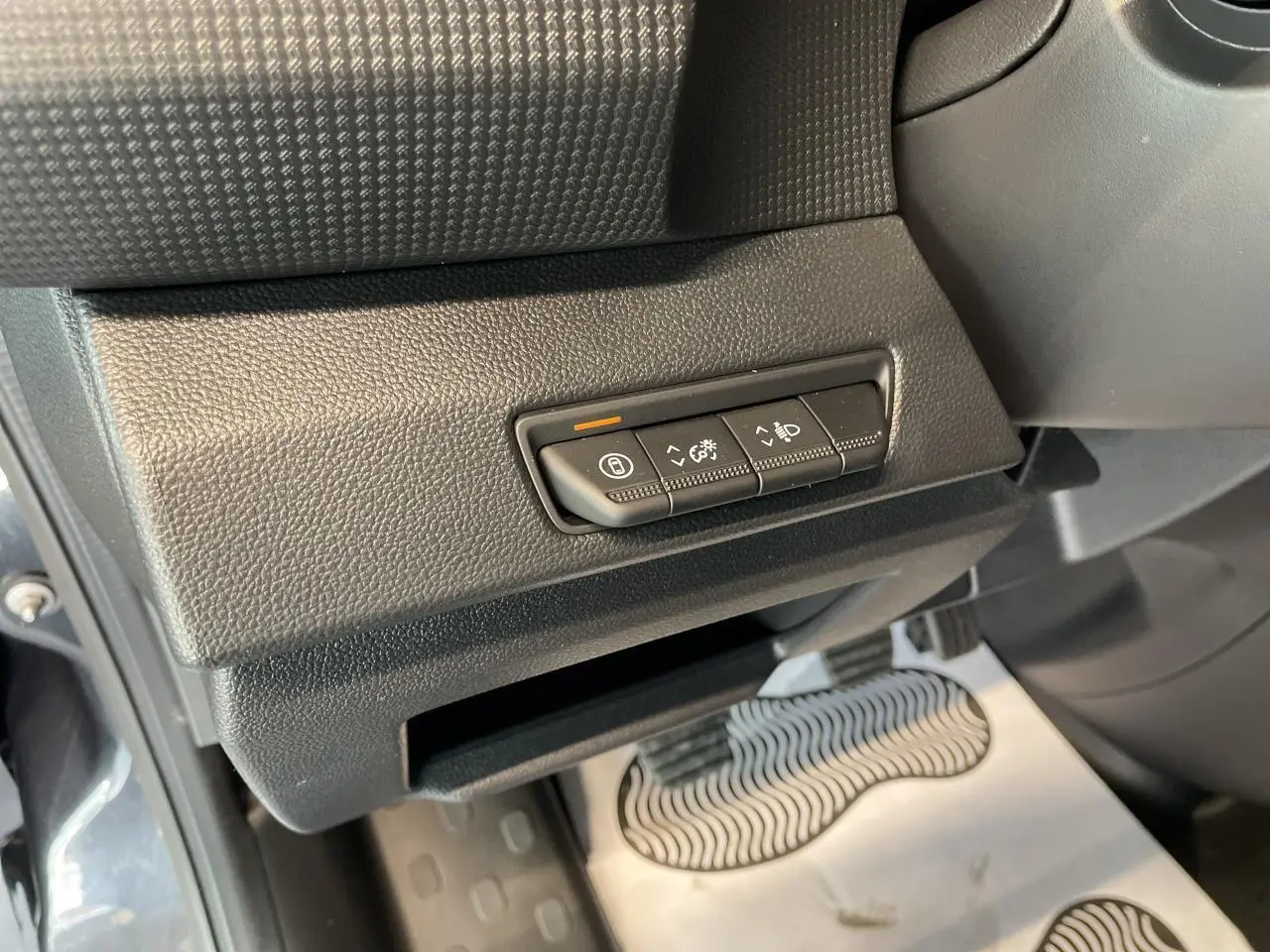 Gros plan sur les commandes d'éclairage et réglages situés sous le tableau de bord côté gauche du Renault Trafic Fourgon gris Comète.