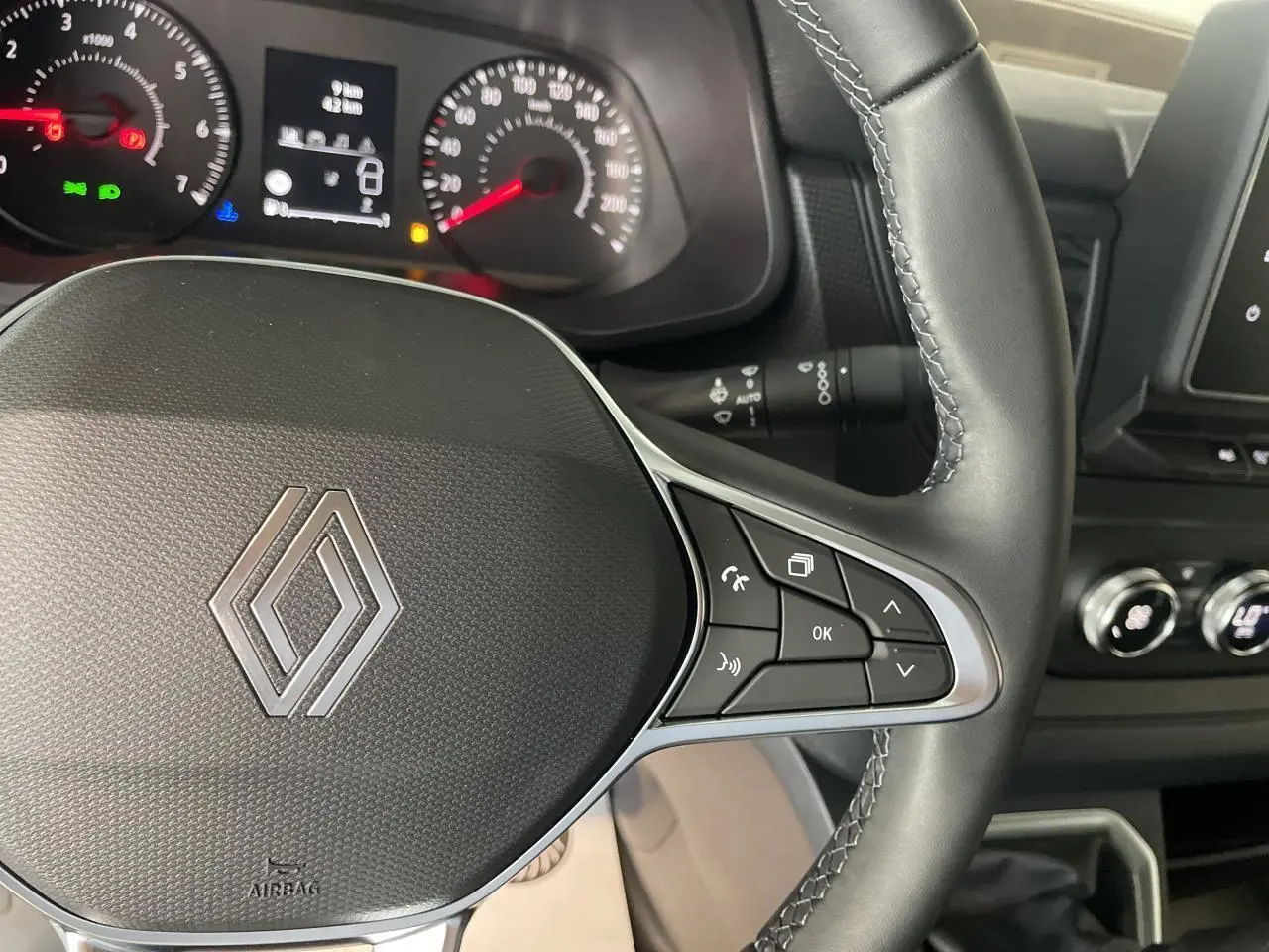 Gros plan sur le volant noir du Renault Trafic Fourgon 2025 avec commandes intégrées et tableau de bord en arrière-plan.