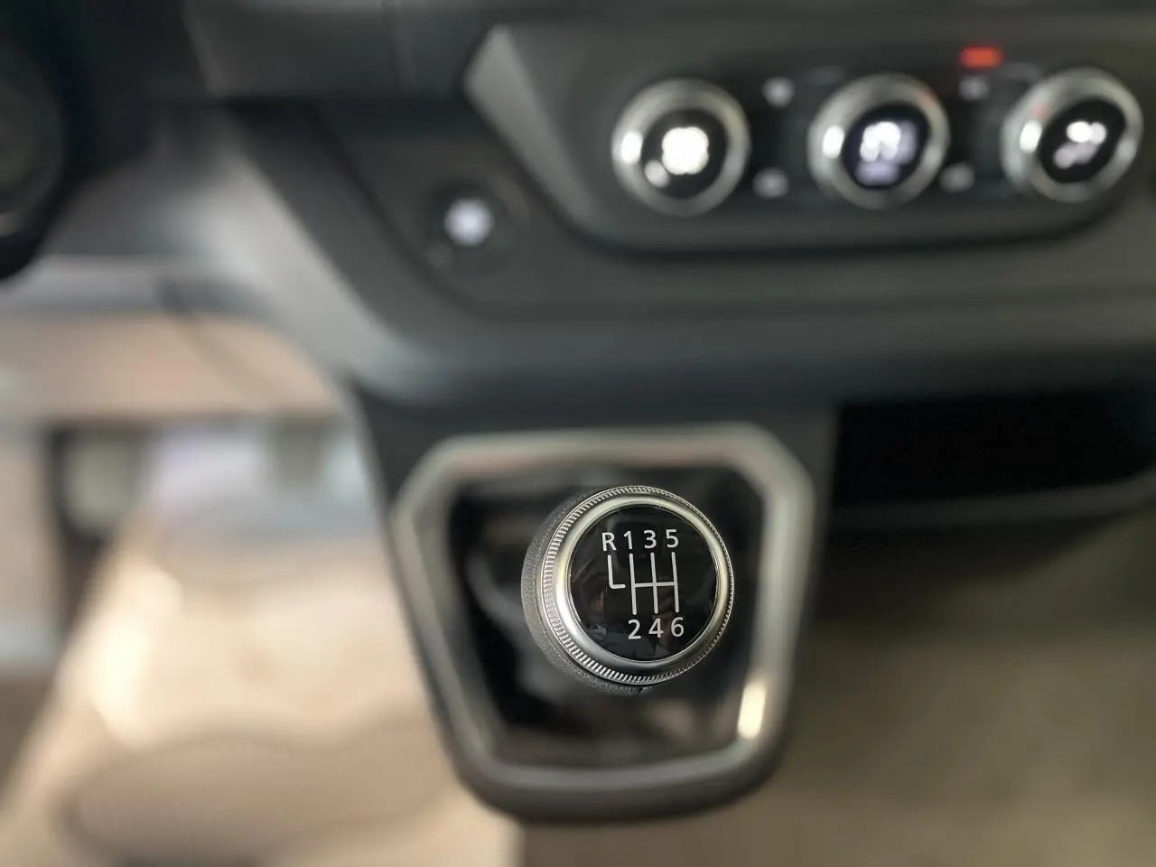 Gros plan sur le levier de vitesses manuel du Renault Trafic Fourgon L2H1, avec commandes de climatisation en arrière-plan.