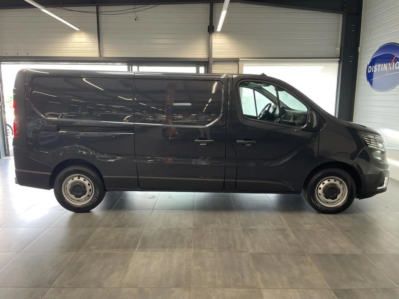 Profil côté droit du Renault Trafic Fourgon L2H1 2025 en gris comète, avec jantes tôles 16 pouces et porte coulissante.