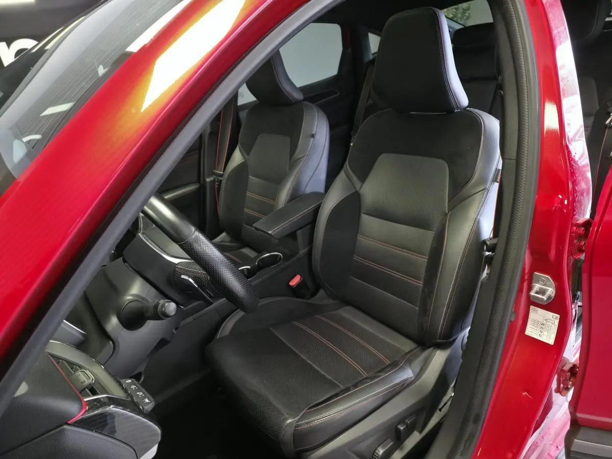 Intérieur avant droit du Renault Arkana rouge avec sièges cuir suédine noirs et surpiqûres rouges R.S. Line