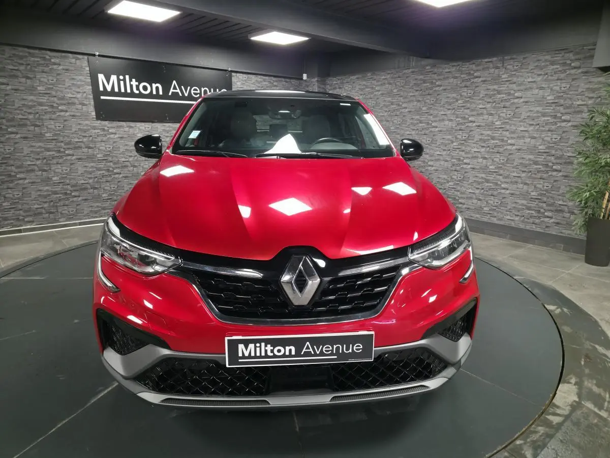 Vue frontale d'un Renault Arkana rouge flamme avec calandre noir brillant et logo Renault centré.