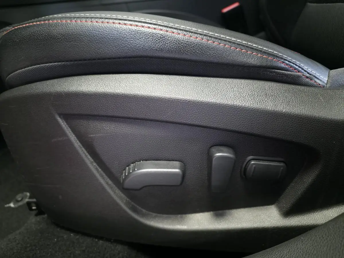 Détail des commandes électriques de réglage du siège avant avec surpiqûres rouges dans Renault Arkana Rouge Flamme 2023.