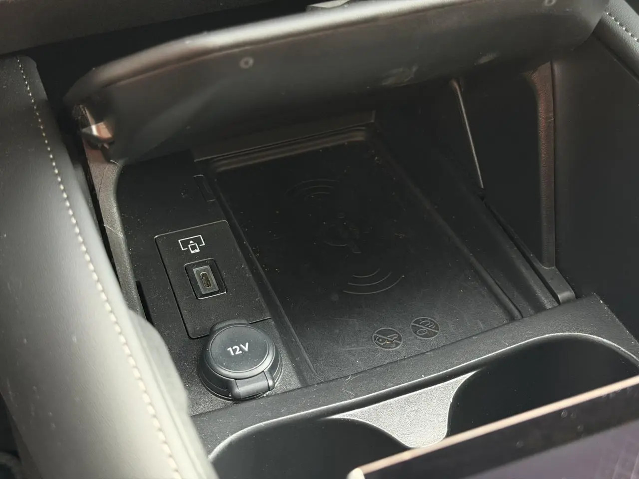 Vue rapprochée de la console centrale noire du DS4 2025 avec chargeur sans fil et prise 12V visible.