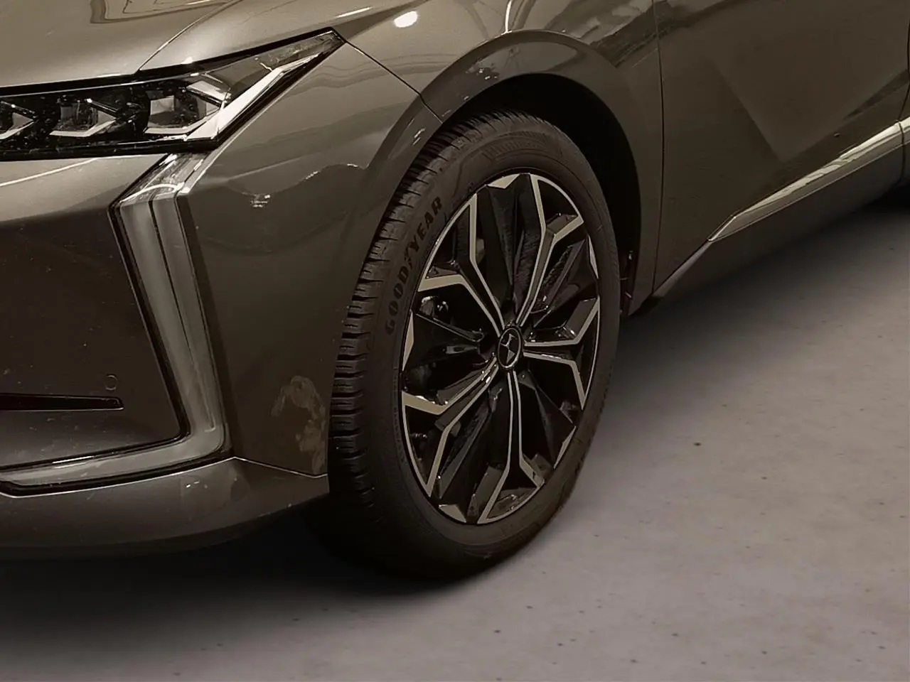 Gros plan sur la roue avant gauche et le phare du DS4 2025 gris Platinium avec jante alliage noire et chromée.