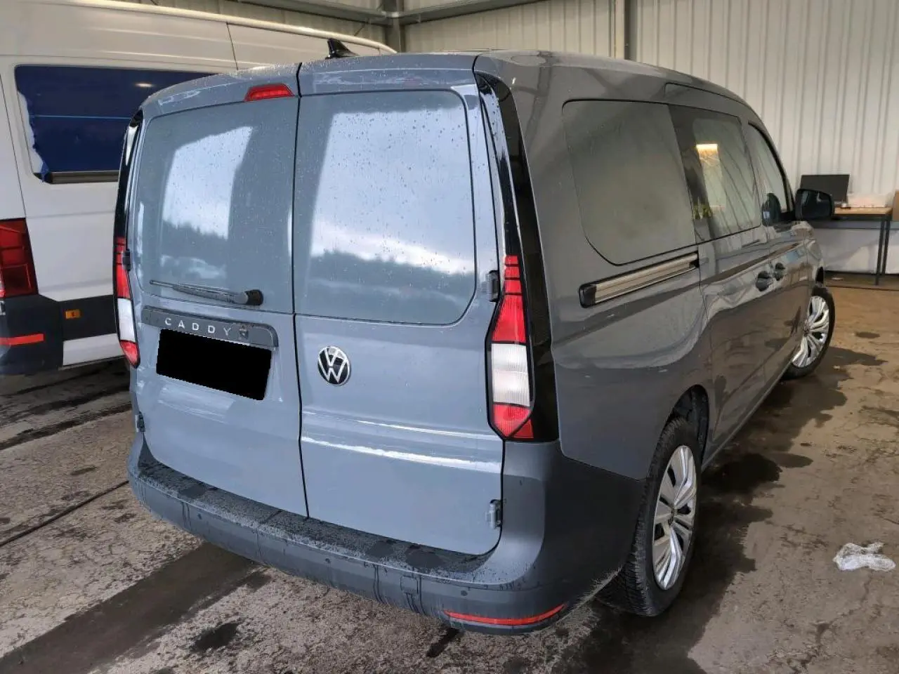 Vue 3/4 arrière droite d'un Volkswagen Caddy Maxi 2024 gris Pure Grey avec portes arrière battantes tôlées et porte latérale coulissante.