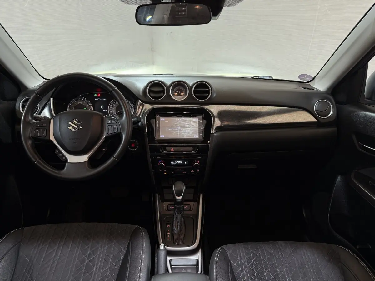 Vue intérieure frontale du tableau de bord noir du Suzuki Vitara 1.5 Dualjet hybrid STYLE avec volant cuir alu multifonctions.