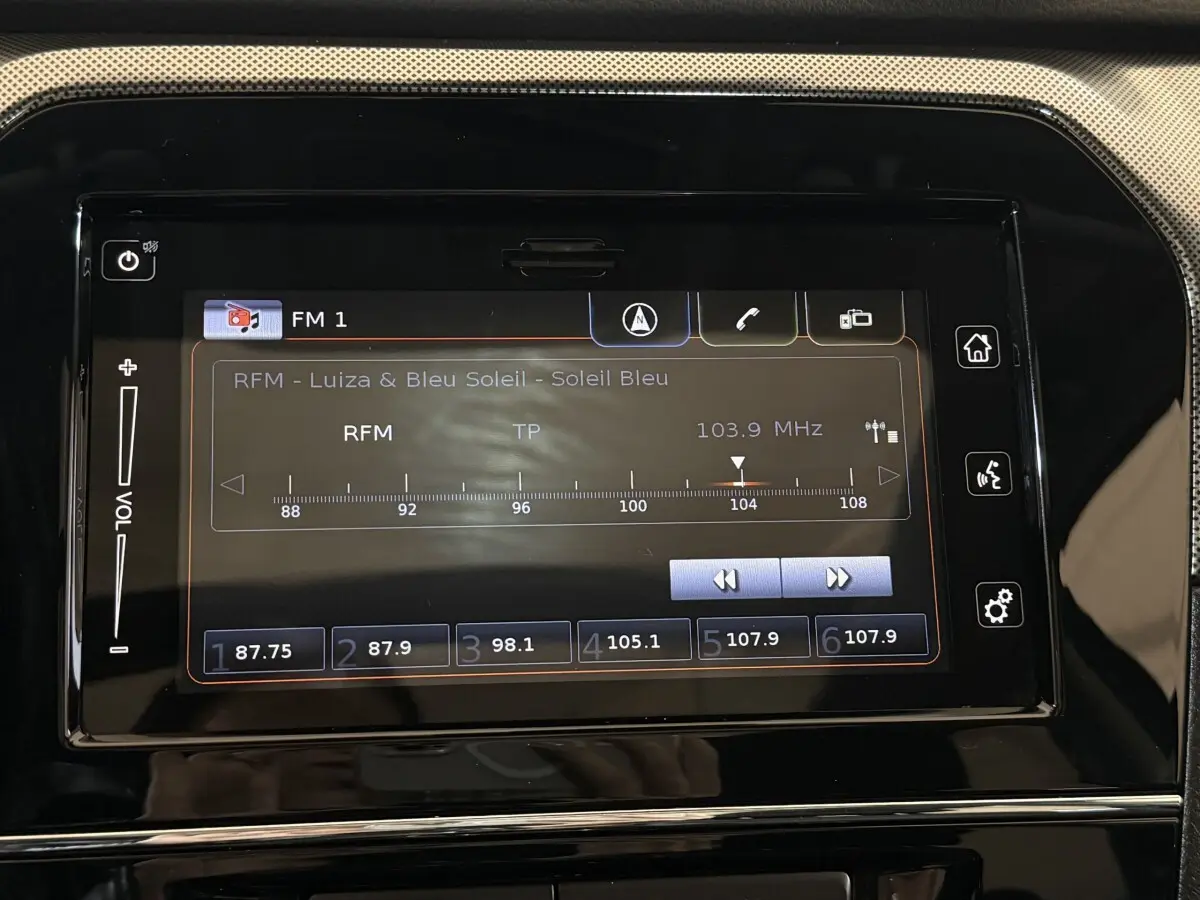 Écran tactile central du tableau de bord du Suzuki Vitara noir, affichant la radio FM sur 103,9 MHz.