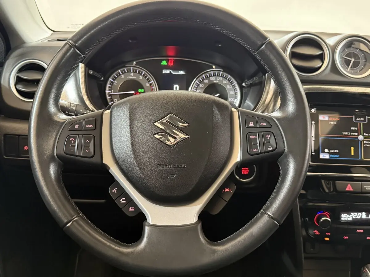 Vue rapprochée du volant cuir et alu noir du Suzuki Vitara 2022 avec tableau de bord et écran tactile visible.