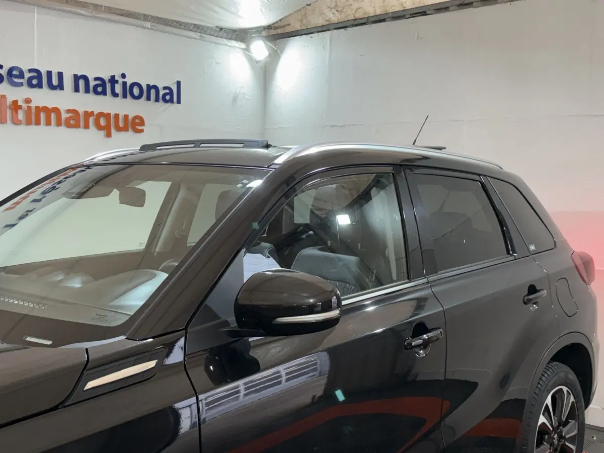 Vue latérale droite du Suzuki Vitara noir 2022 avec toit ouvrant et rétroviseur noir brillant.