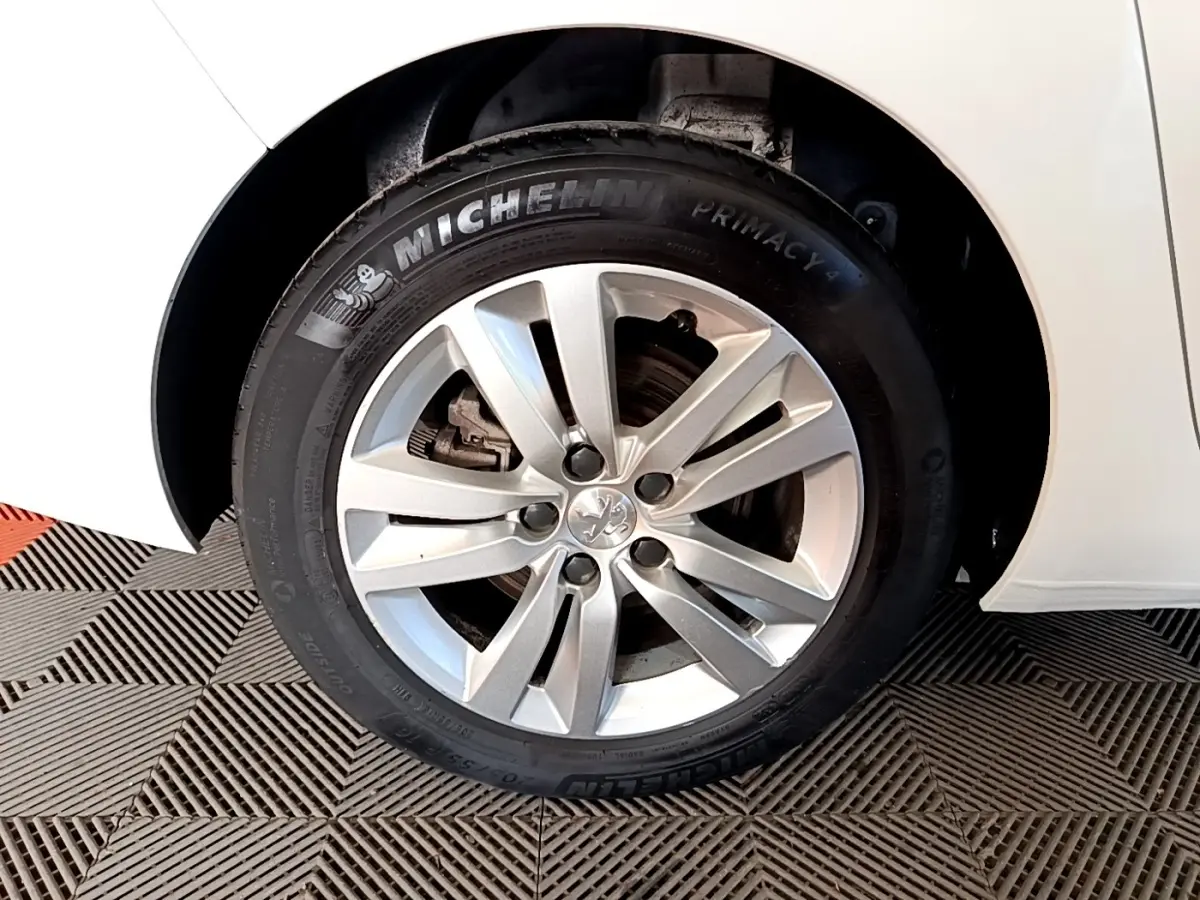 Vue rapprochée de l'aile arrière droite d'une Peugeot 308 blanche, mettant en valeur la roue et le passage de roue.